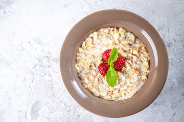 Healthy breakfast. Baked granola with milk and raspberries with mint in a plate. Tasty muesli, close-up