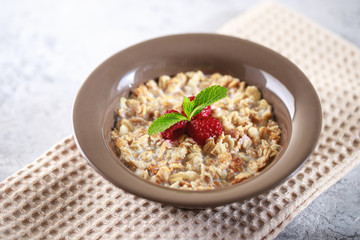 Baked granola with milk and raspberries with mint in a plate. Healthy breakfast. Tasty muesli, snack. top shot
