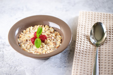 Baked granola with milk and raspberries with mint in a plate. Healthy breakfast. Tasty muesli, snack. top shot