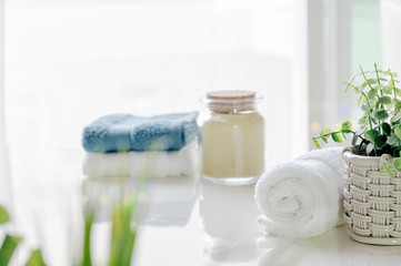 Mockup bath towels on white table with houseplant in white room, copy space for product display.