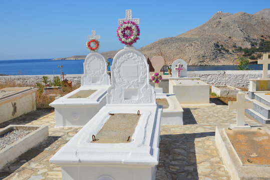 Typische stilvolle Grabgestaltung auf dem Friedhof von Emborios oder Imborios auf der griechischen Insel Chalki mit der südlich gelegenen Bucht im Hintergrund 9 km nördlich von Rhodos