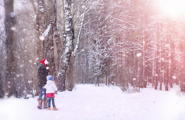 Fototapeta na wymiar A winter fairy tale in the forest. A girl on a sled with gifts on the eve of the new year in the park. Two sisters walk in a New Year's park and ride a sled with gifts.
