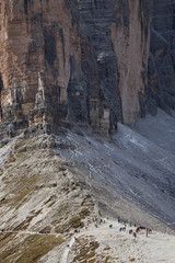 Fototapeta na wymiar tourists at the foot of a giant rock in the Dolomites