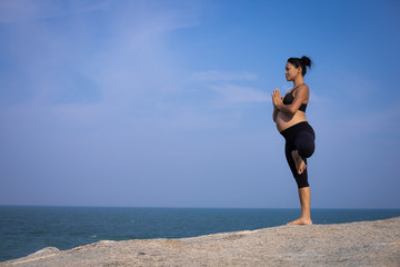  Asian pregnant woman yoga on the beach sunset summer time