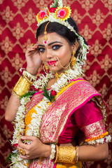 Fototapeta na wymiar Traditional Bengali woman in wedding sari and makeup with flowers and garland, Indian woman looking at camera