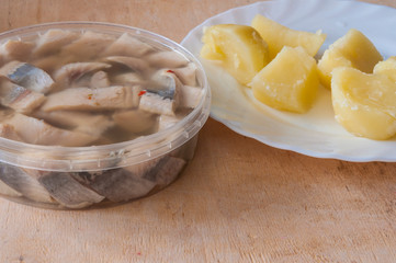 Salted herring and boiled potatoes on white plate