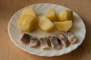 Salted herring and boiled potatoes on white plate
