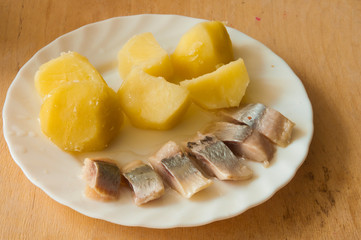 Salted herring and boiled potatoes on white plate