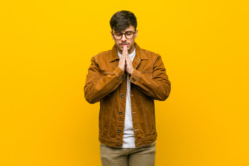 Young hispanic casual man holding hands in pray near mouth, feels confident.