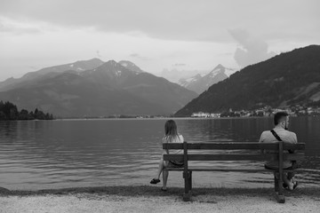A young couple sits on the lake, a quarrel between a guy and a girl, gender problems, relationships, stress and depression, a spoiled weekend, vacation Zell am see Austria, copy space, black and white