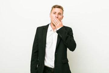 Young caucasian business man yawning showing a tired gesture covering mouth with hand.
