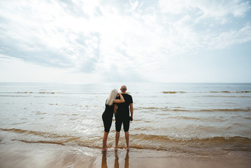 Man and woman standing on the beach and looking to the sea and blue sky