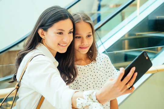 arabian mother and daughter talking selfie after shopping on phone camera or video shat online escalator background