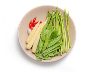 Fresh chili, garlic,  peas, baby corn and asparagus in a dish for vegetables stir frying isolated on white