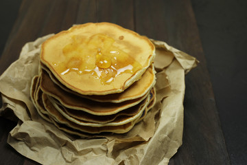 stack of pancakes with honey on a black background