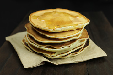 stack of pancakes with honey on a black background