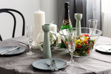 Closeup of dinner table set with Salad and wine, plates and candles