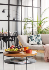 Coffee and fruits on small wooden coffee table in elegant dining and living room interior