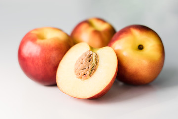 Ripe red, orange and yellow nectarines, peaches, apples on a white table. Tasty bright fruits. Healthy eating. Isolated object.