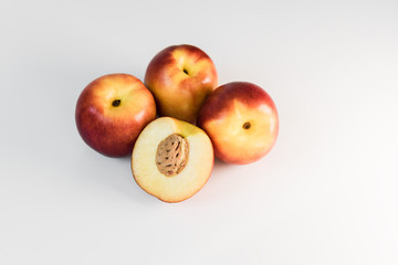 Ripe red, orange and yellow nectarines, peaches, apples on a white table. Tasty bright fruits. Healthy eating. Isolated object.