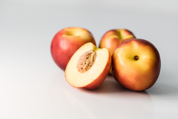 Ripe red, orange and yellow nectarines, peaches, apples on a white table. Tasty bright fruits. Healthy eating. Isolated object.