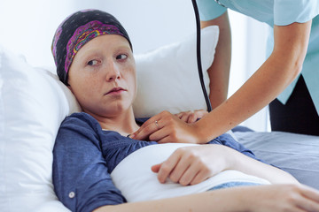 Young female doctor examining young sick woman with cancer at hospital