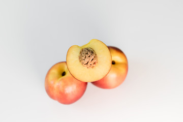 Ripe red, orange and yellow nectarines, peaches, apples on a white table. Tasty bright fruits. Healthy eating. Isolated object.