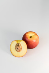 Ripe red, orange and yellow nectarines, peaches, apples on a white table. Tasty bright fruits. Healthy eating. Isolated object.