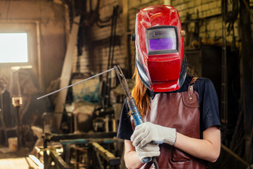 Strong and worthy pretty redhead ginher woman wearing protection helmet and leather apron with...