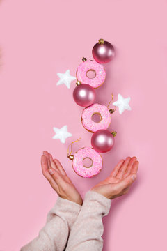 Pink Christmas decoration balls, stars and donuts is falling on pink background. Levitation concept.