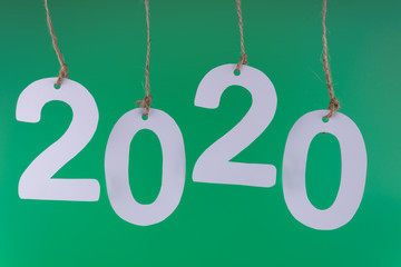 Twenty twenty numbers hanging on decorative ropes, highlighted in closeup on a green background