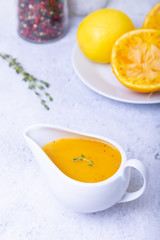 Orange sauce for duck (poultry) in a white gravy boat. Close-up, selective focus.