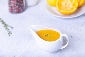 Orange sauce for duck (poultry) in a white gravy boat. Close-up, selective focus.