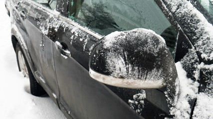 Melting snow and ice from the car. Car's side view mirror.