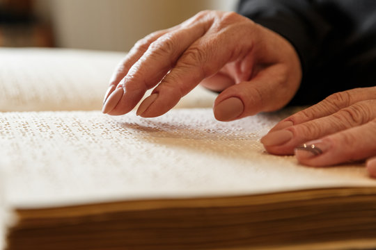 woman reading braille text on old book