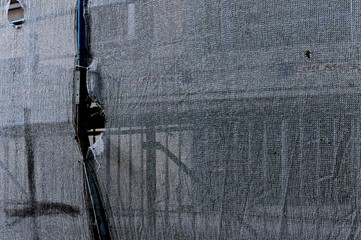 Detail of a rusty scaffolding through a white plastic fiber net - Abstract background (Pesaro,...