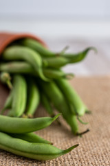 Close-up of green beans on burlap, in the background defocused beans on white background, in vertical