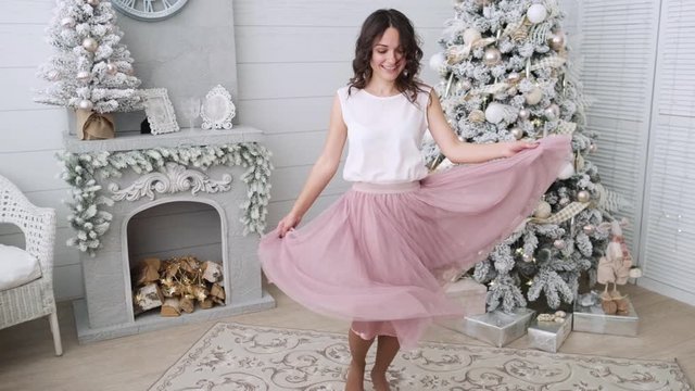Beautiful girl woman near christmas tree smiling dancing in beautiful dress in decorated house, happy new year.