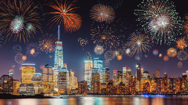 New Years Eve with colorful Fireworks over New York City skyline long exposure with dark blue-purple sky, orange city light glow and reflections in the river