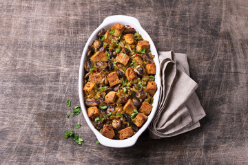 Vegan Stuffing with Mushrooms, Leeks and crunchy croutons on wooden table, top view, horizontal. Thanksgiving traditional meal