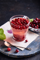 cranberry juice with honey in a cup, cranberries in sugar. On a dark wooden background Copyspace