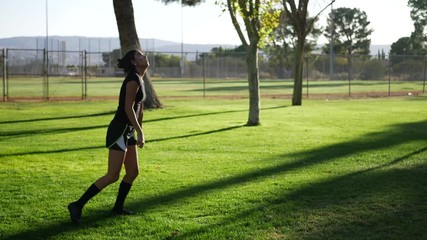 A hispanic woman athlete practicing soccer skills juggling a football at a team sport practice in the park.
