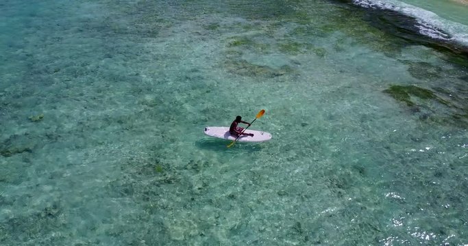 sitting man paddling in sea water of barbados