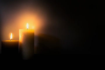 Two burning brightly candles in the dark shadow, space for text romantic colorful concept background