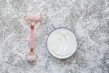 Pink quartz face roller on grey background.