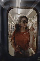 Beautiful girl in a red shirt and blue jeans in a subway train car.