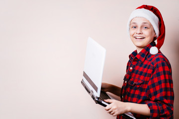 Teenage boy in christmas hat using laptop, copy space. Black friday and holiday sale concept