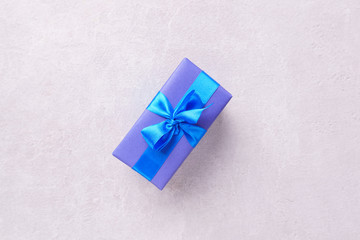 Present box in wrapping paper and tied with satin ribbon on stone background, copy space. Father's day, birthday, Valentine' s day gift