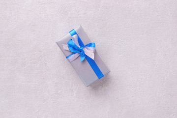 Present box in wrapping paper and tied with satin ribbon on stone background, copy space. Father's...