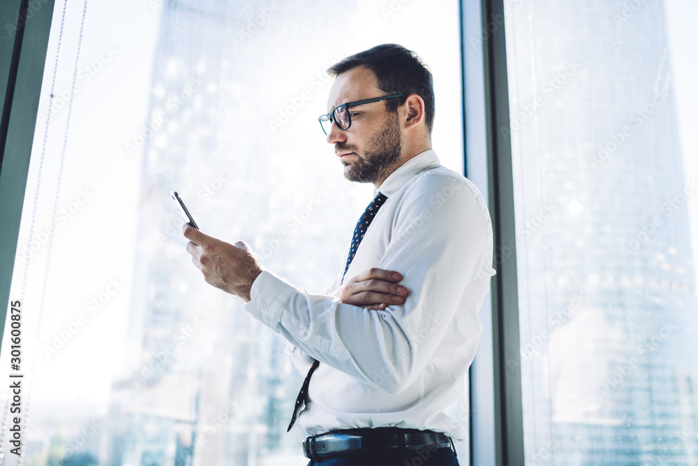 Poster side view of concentrated man checking sms message via smartphone gadget using 4g connection indoors
